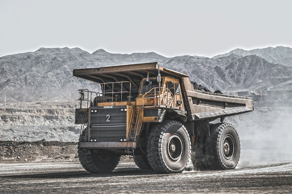 Yellow mining haul truck driving along a dusty site road