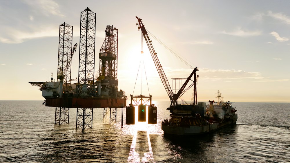 Offshore platforms and a support vessel at sea at sunset